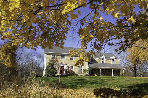 A house with some leaves that have changed colors have begun to fall.