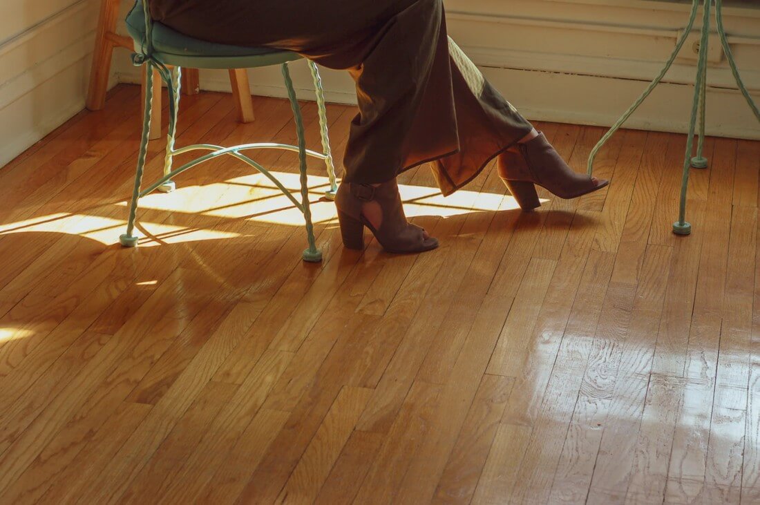 A homeowner sits on a chair that rests on top of her fresh hardwood floors.