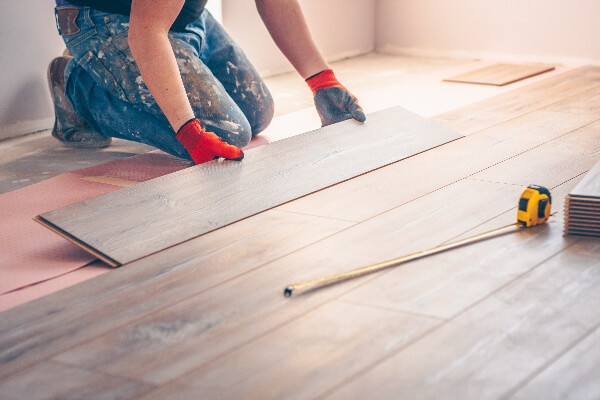 A professional home remodeling contractor installs hardwood flooring in a client's home.